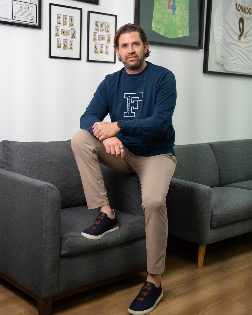 Andrew Grepe en su oficina, con su colección de jerseys enmarcados